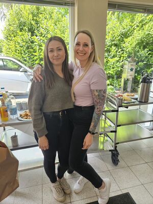Zwei Frauen stehen in einem Raum und halten sich im Arm.