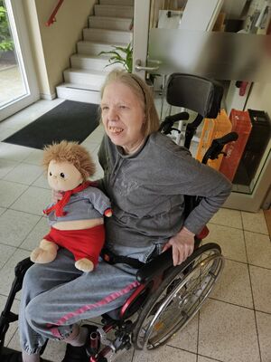 Eine Frau im Rollstuhl hat eine Puppe in der Hand.