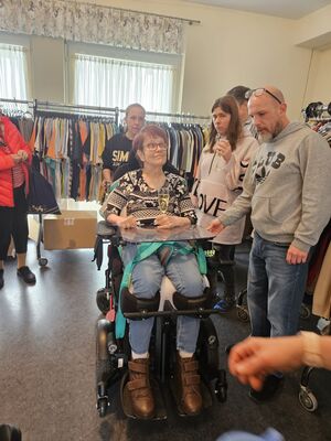 Mehrere Personen stehen bei einer Frau im Rollstuhl.