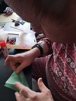 Eine Person bastelt etwas aus grünem Papier.