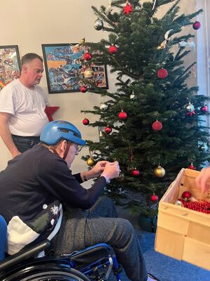 Eine Person im Rollstuhl mit Helm schmückt den Baum.