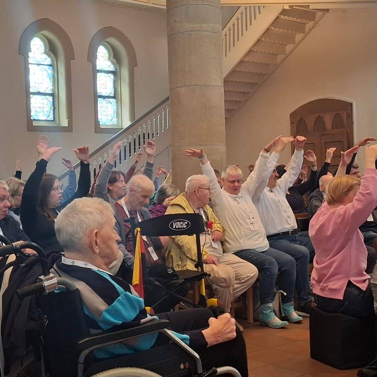Menschen sitzen in der Kirche und strecken die Arme in die Höhe.