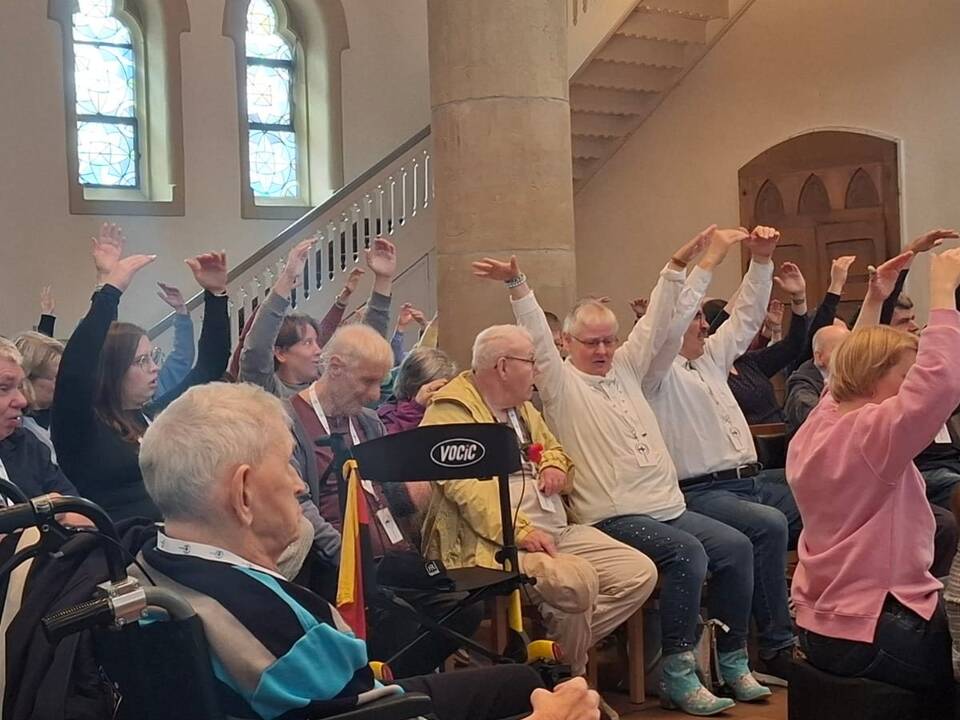 Menschen sitzen in der Kirche und strecken die Arme in die Höhe.