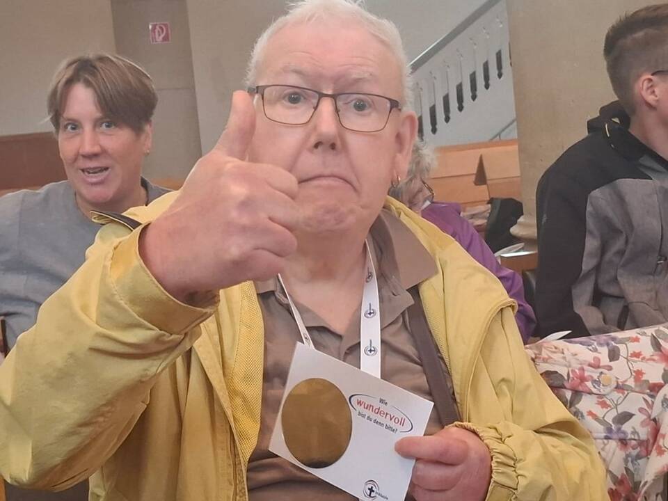 Ein Mann zeigt den Daumen nach oben und hält eine Karte in der Hand.