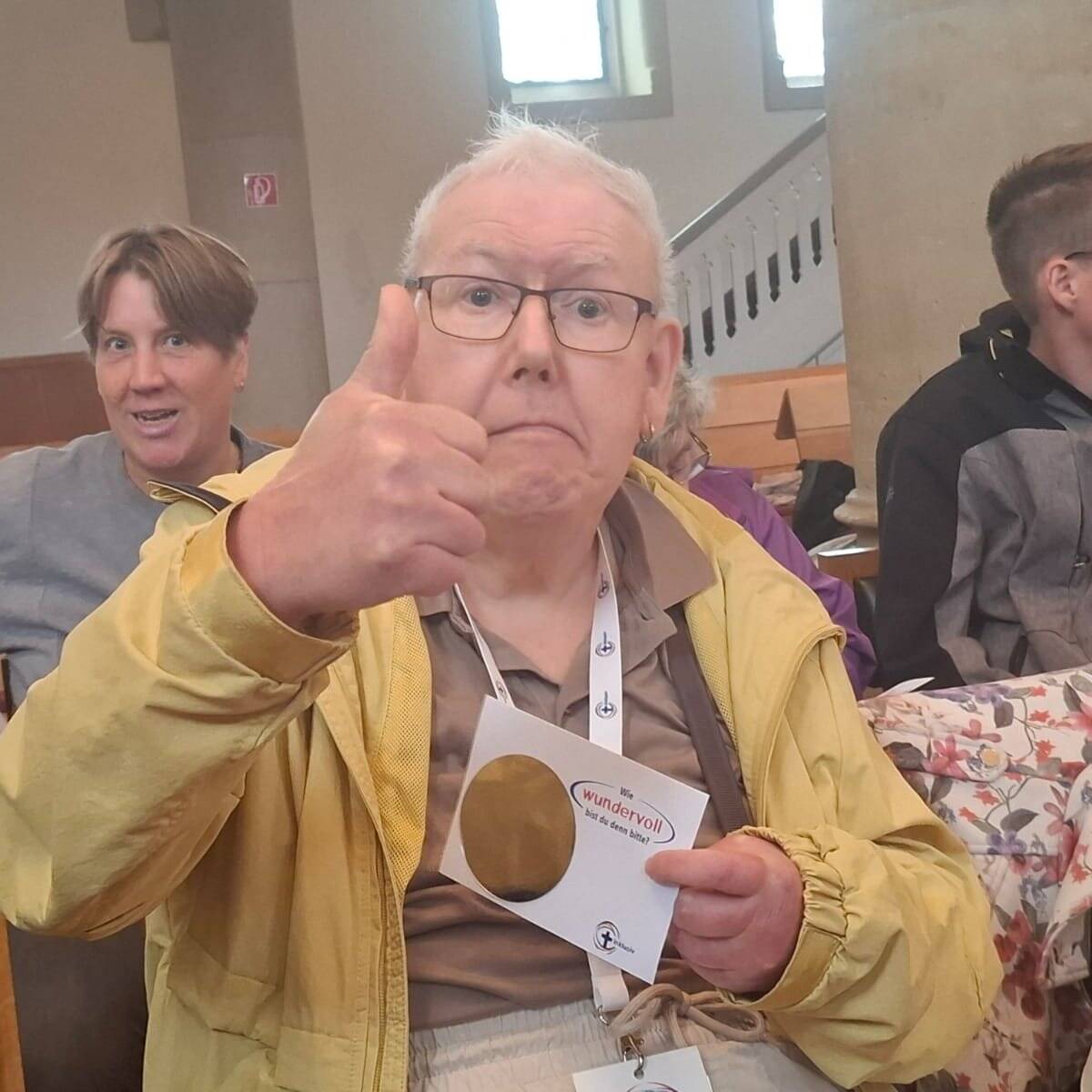 Ein Mann zeigt den Daumen nach oben und hält eine Karte in der Hand.