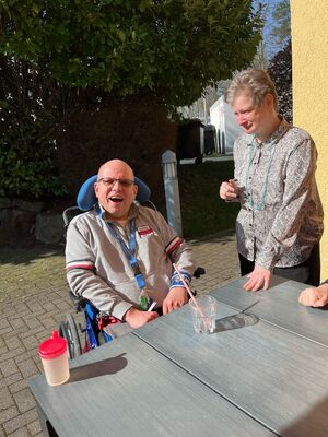 Zwei Personen an einem Tisch, draussen in der Sonne.