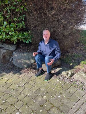 Eine Person sitzt auf einer STeinmauer in der Sonne.