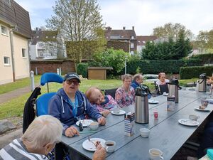 Einige Bewohner sitzen am Tisch, trinken Kaffee und essen Kuchen.