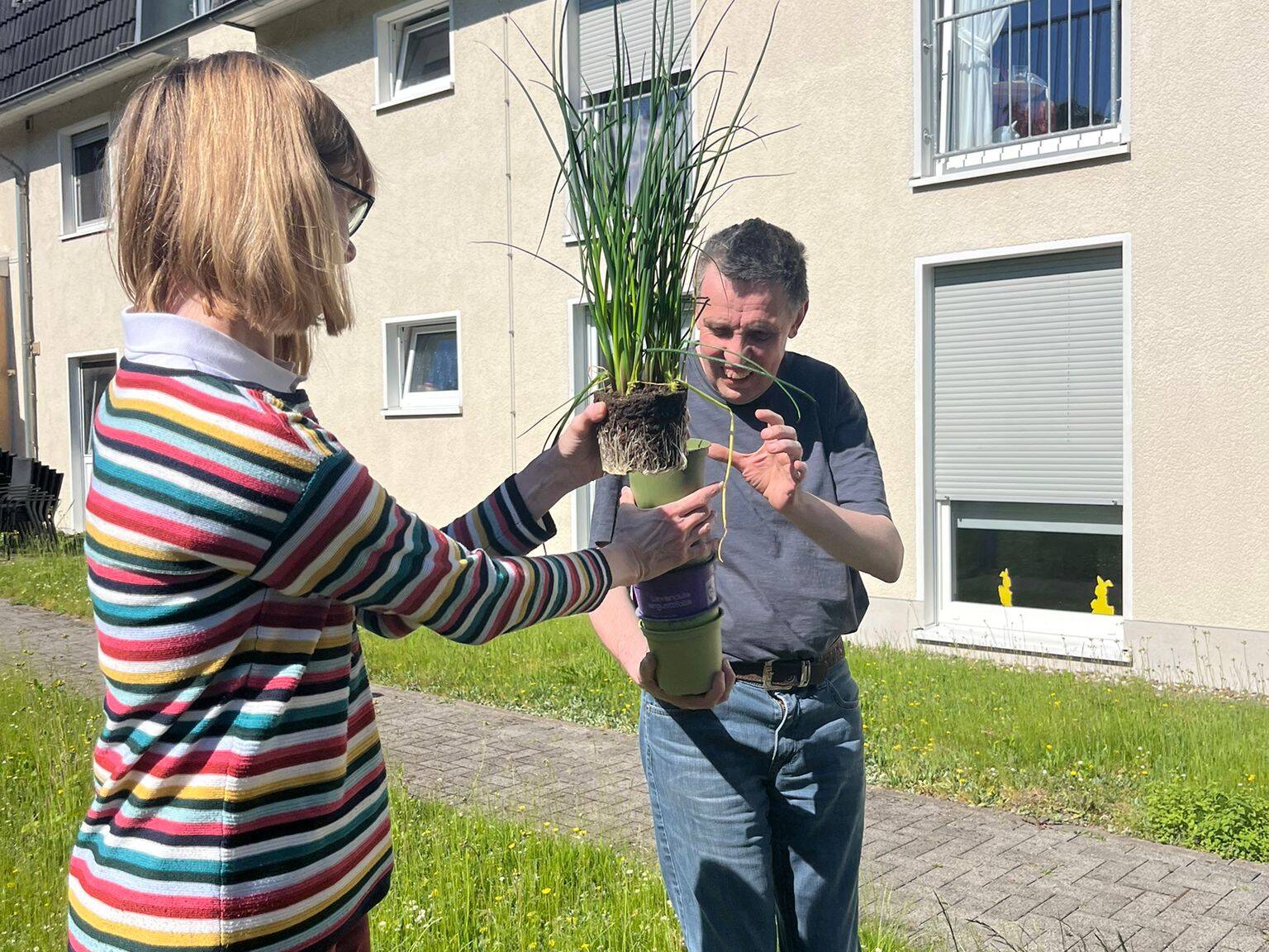 Zwei Personen mit einer Pflanze in der Hand.