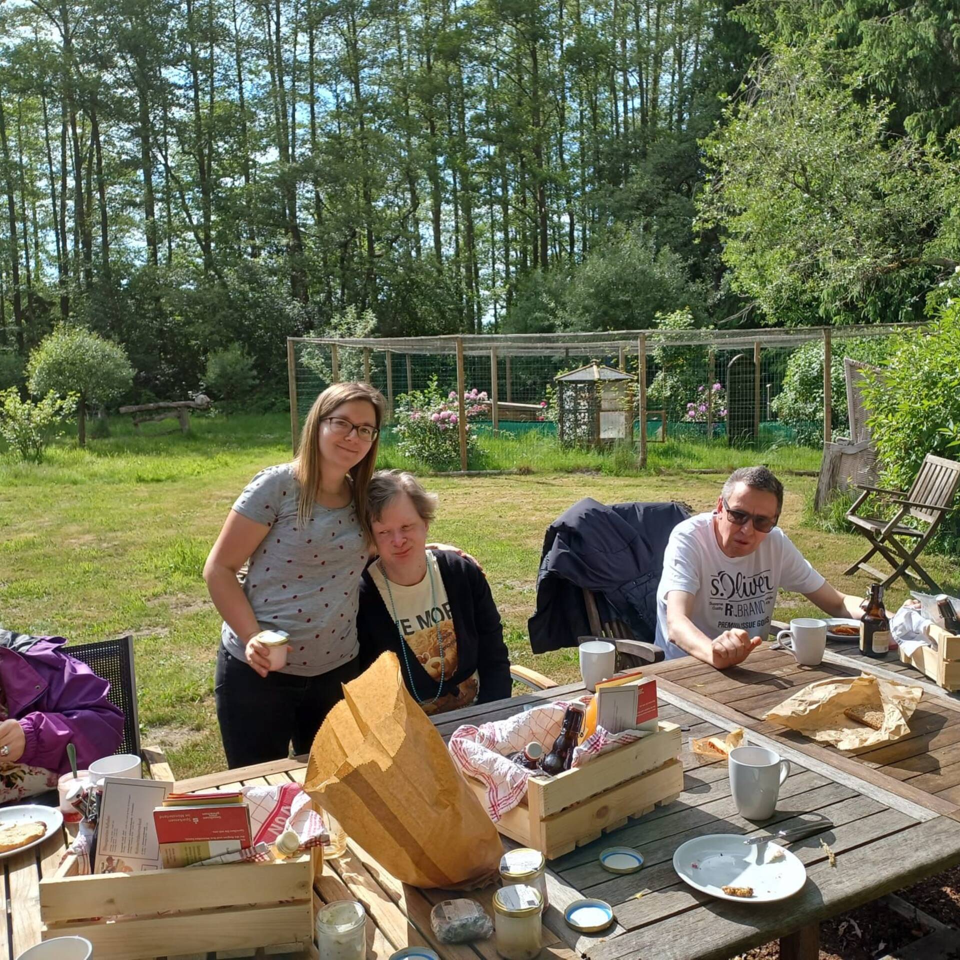 Personen sitzen draußen an einem gedeckten Tisch.