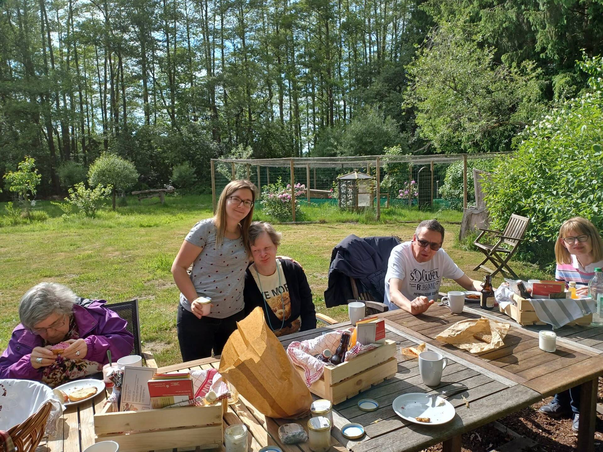 Personen sitzen draußen an einem gedeckten Tisch.