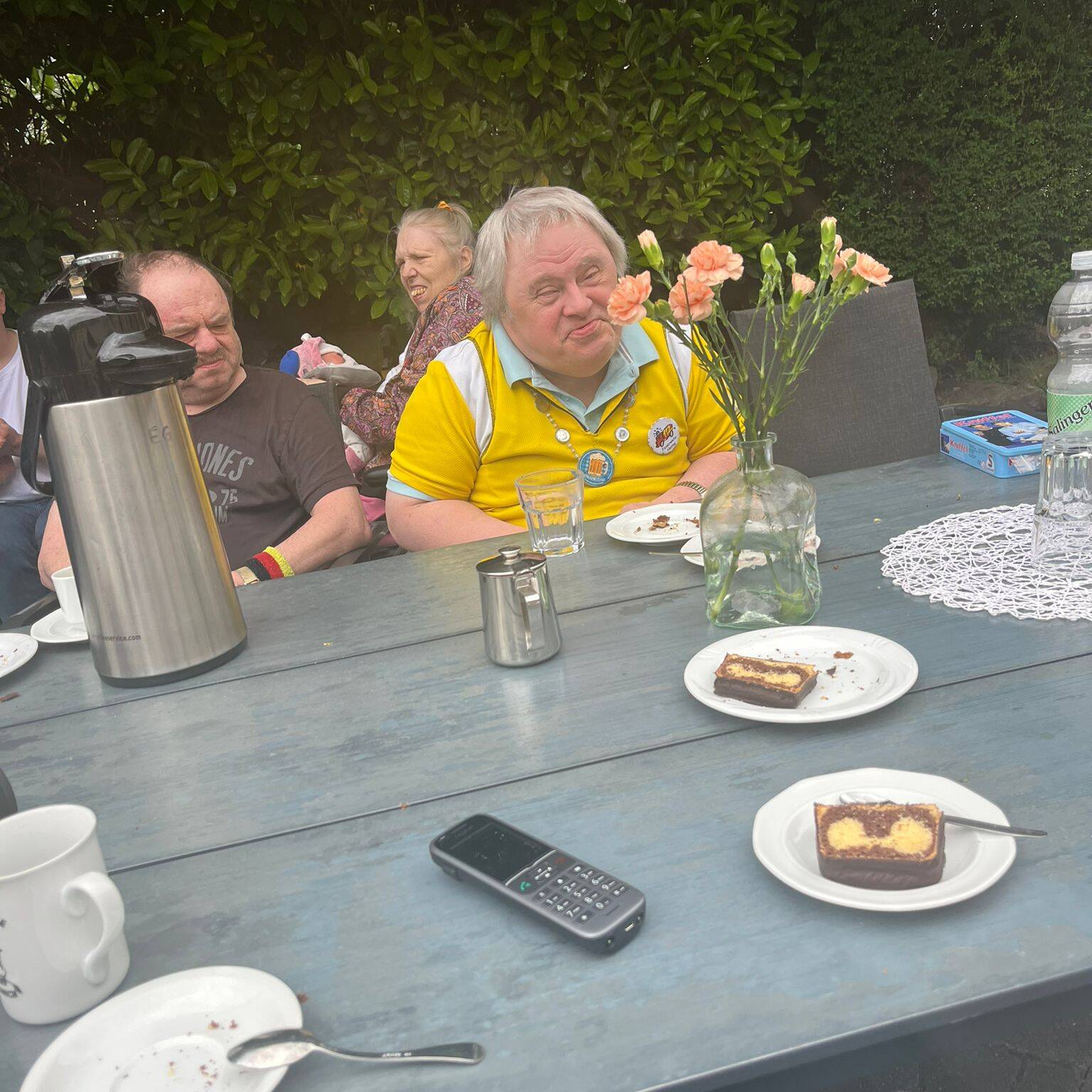 Eine Person sitzt am Tisch, Kuchen liegt auf Tellern.