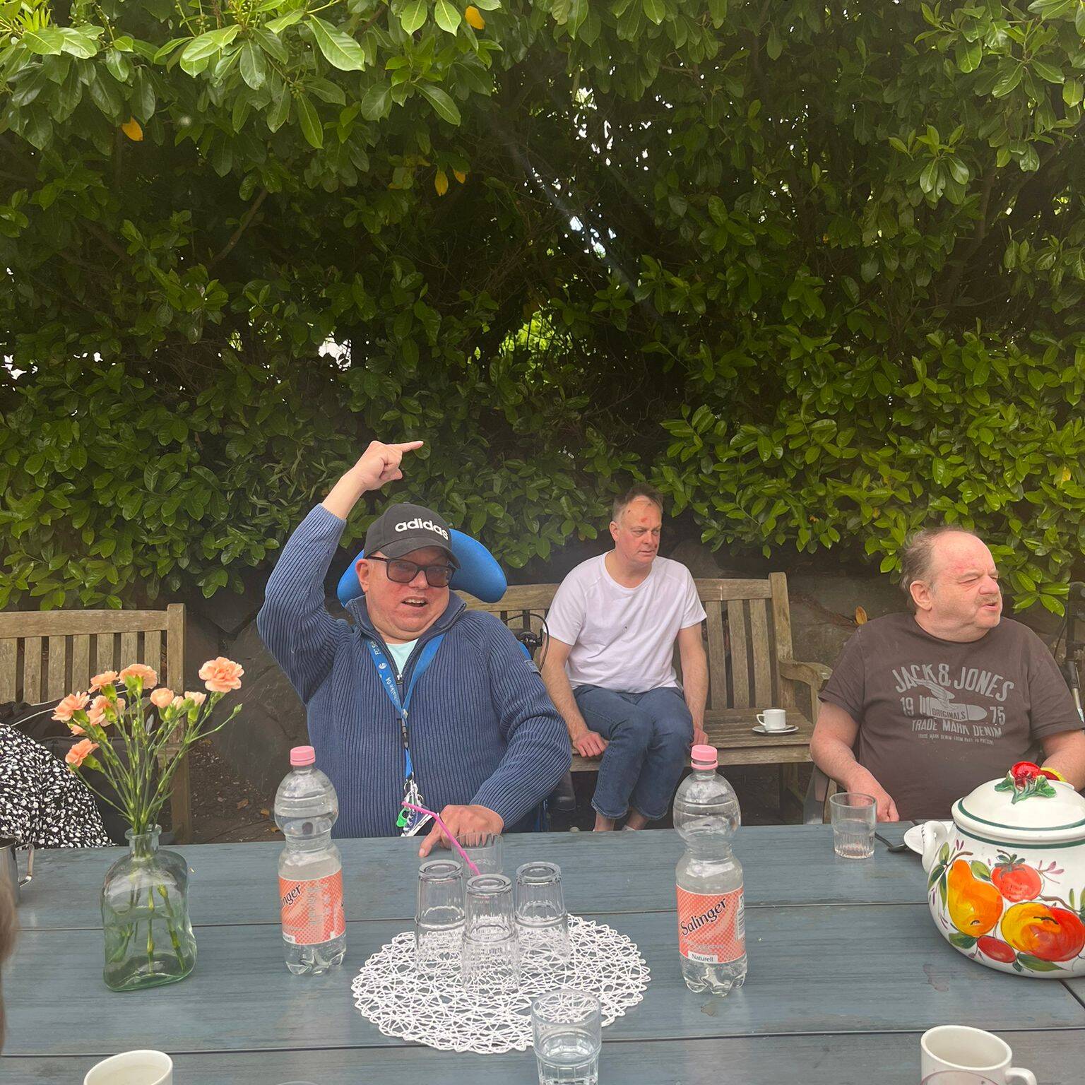 Mehrere Männer sitzen am Gartentisch.