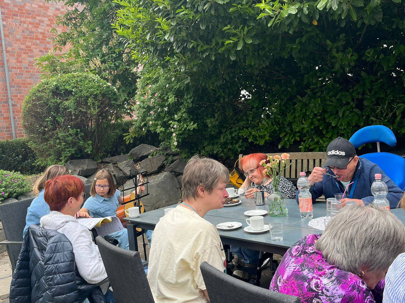 Mehrere Bewohner sitzen draussen an einem Tisch.