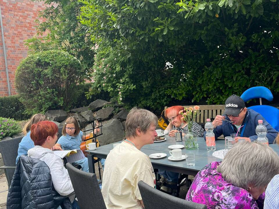 Mehrere Bewohner sitzen draussen an einem Tisch.