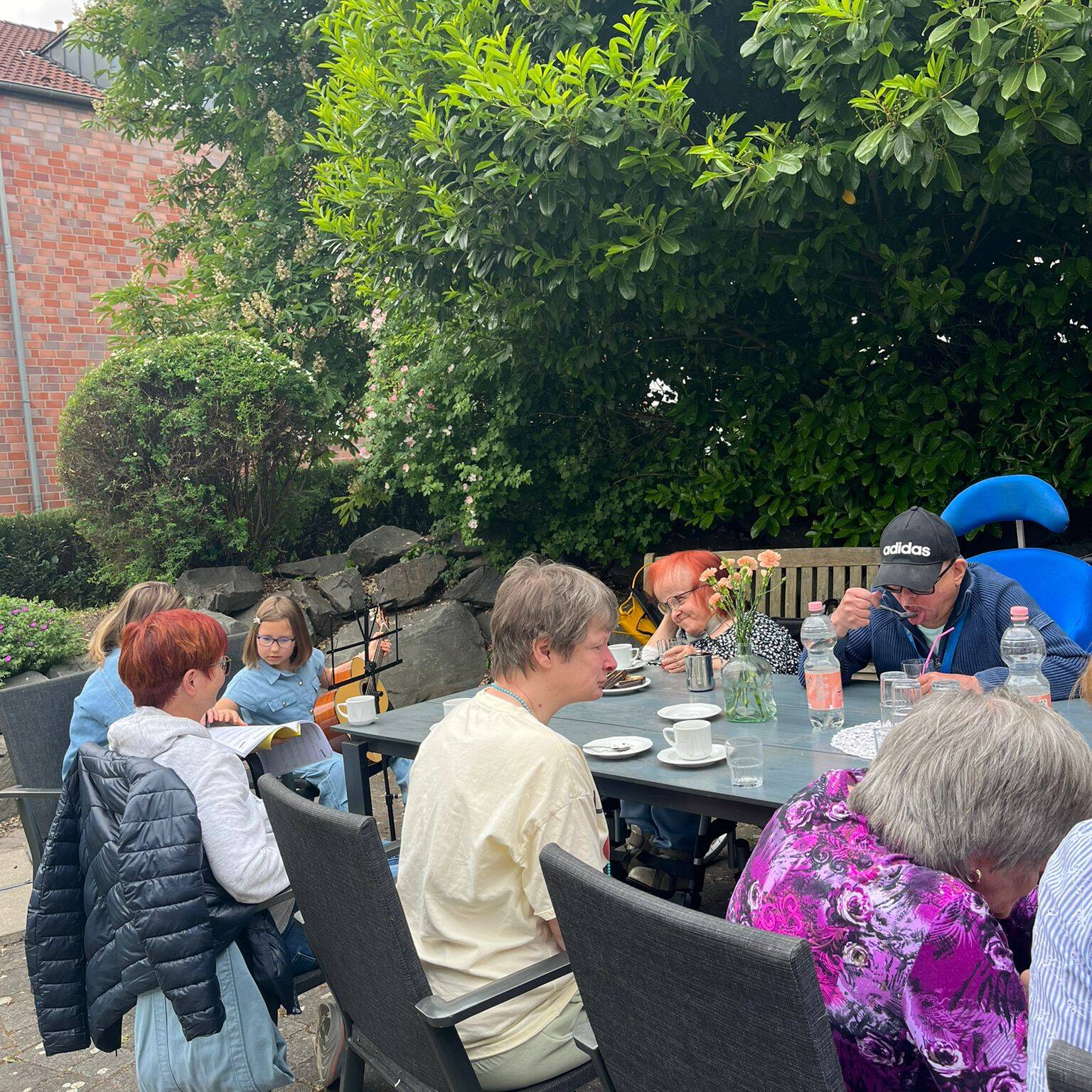 Mehrere Bewohner sitzen draussen an einem Tisch.