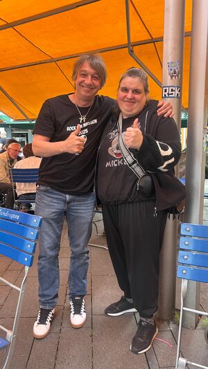 Ein Mann hat eine Frau im Arm und beide zeigen mit dem Daumen nach oben.