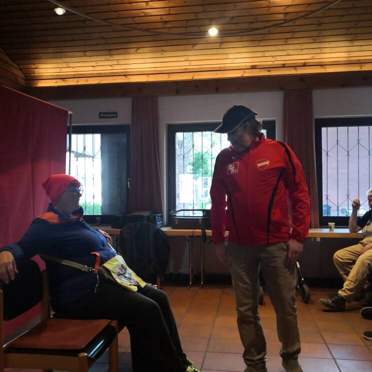 Ein Mann sitzt mit einer roten Mütze auf einem Stuhl.