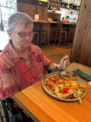 Eine Frau im Rollstuhl sitzt vor ihrem Mittagessen.
