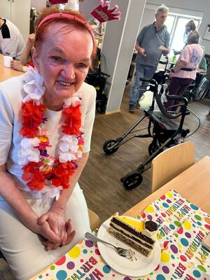 Regina sitzt an einem Tisch, darauf steht ein Teller mit Kuchen.