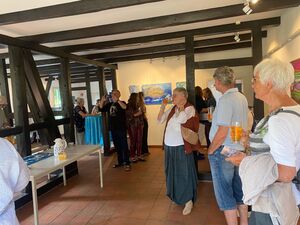 Besucher stehen an Stehtischen in einem Raum