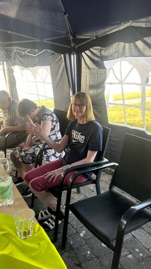 Mehrere Personen sitzen in einem Pavillion am Tisch.