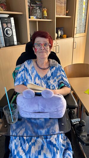 Eine Frau in einem Rollstuhl hat ein blau weißes Kleid an.