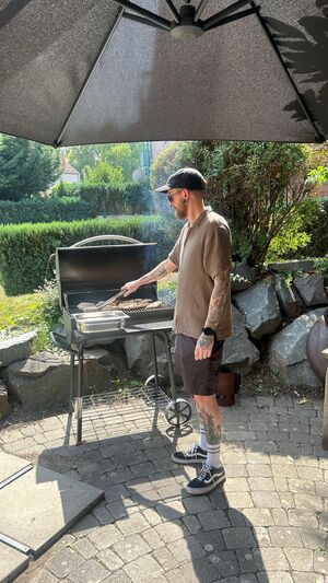 Ein Mann mit Kappe grillt.