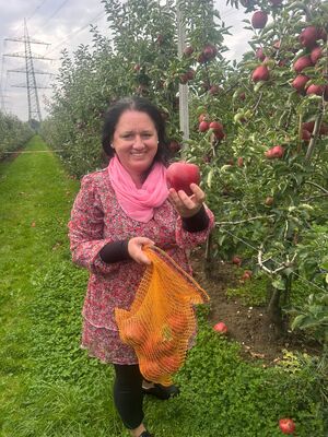 Eine Frau hält einen Apfel in der Hand und ein Netz.
