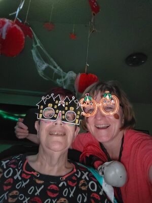 Zwei Frauen mit bunten Brillen lachen.