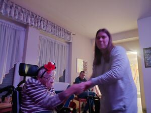 Eine junge Frau hält die Hände einer Rollstuhlfahrerin in die Luft und lächelt.