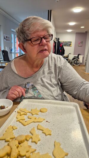 Eine Frau sitzt vor einem Blech mit Plätzchen.