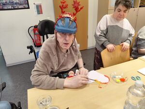 Ein Mann im Rollstuhl mit einem blauen Helm bastelt.