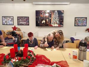 Mehrere Personen sitzen an einem Tisch, darauf steht ein Adventskranz.