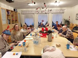 Viele Menschen sitzen an einem großen Tiscsh und sind kreativ.