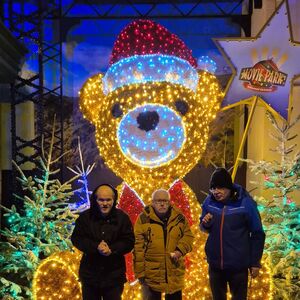 Drei Personen vor einem großen, leuchtenden Teddybär.