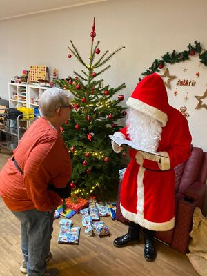 Der Nikolaus liest aus dem Buch vor. Vor ihm steht eine Frau.