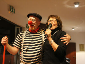 Ein Clown hat eine Frau mit Mikrofon im Arm.