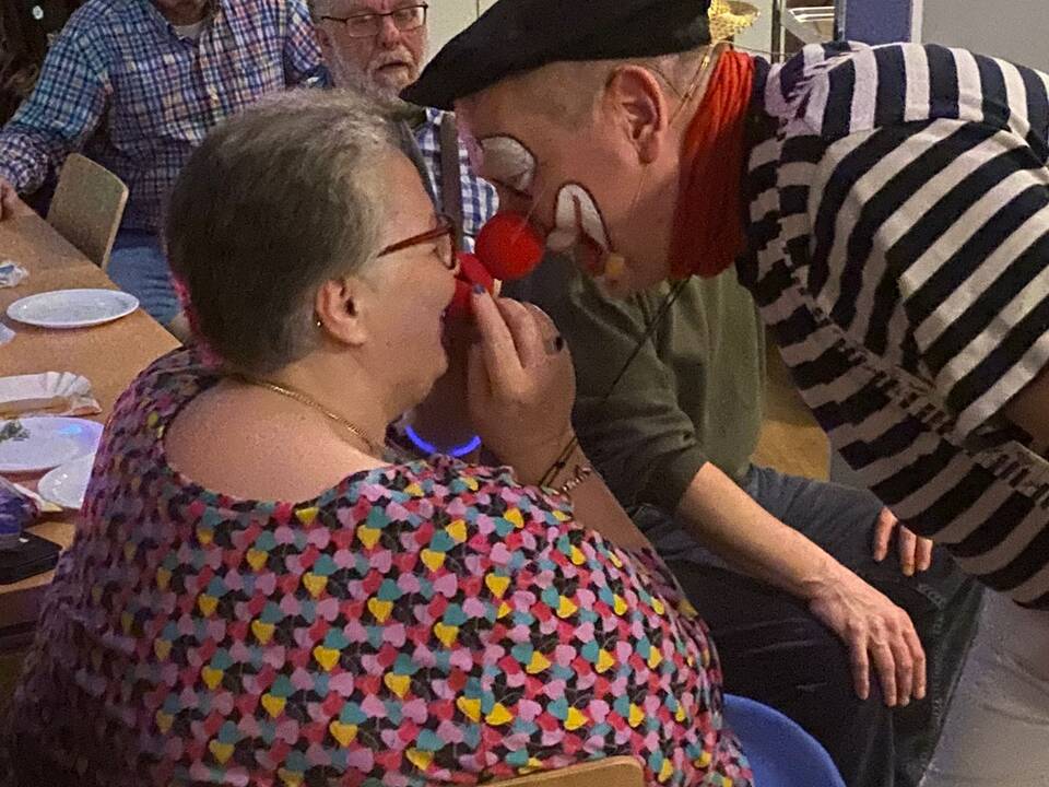 Ein Clown ist ganz dicht mit dem Gesicht an einer Frau.