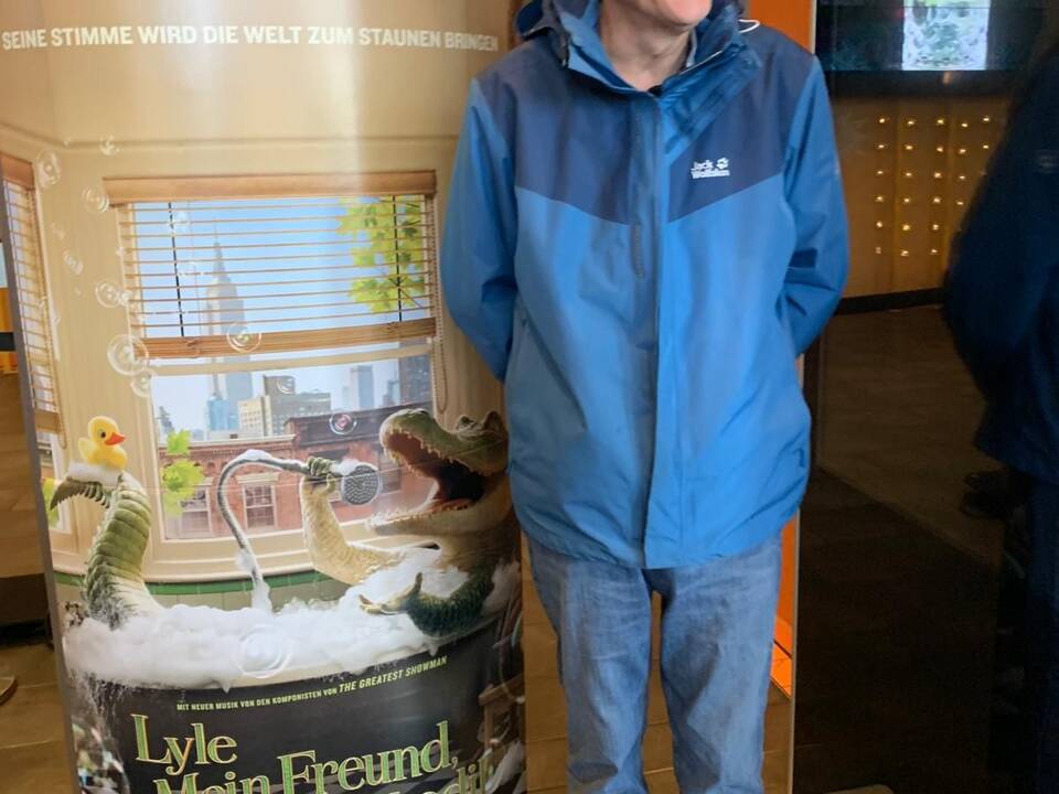 Ein Mann neben einem Aufsteller mit Werbung für den Film.