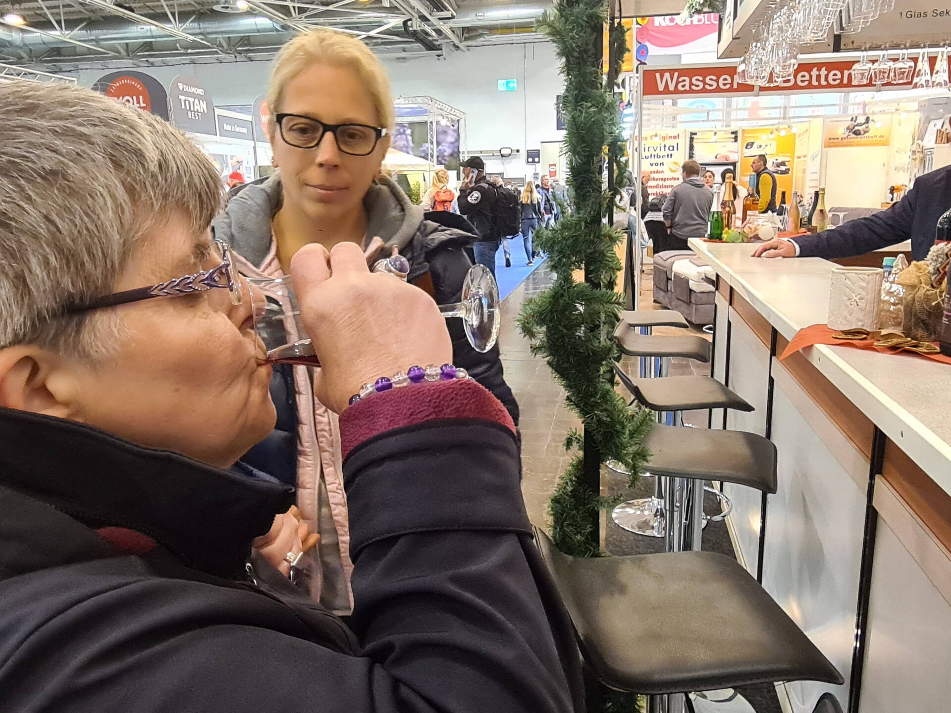 Eine Frau trinkt etwas, eine andere schaut ihr dabei zu.