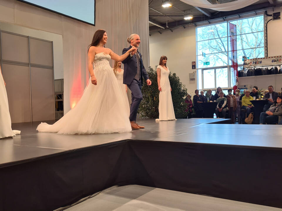 Models mit Brautkleidern, eine Model wird von einem Mann geführt.