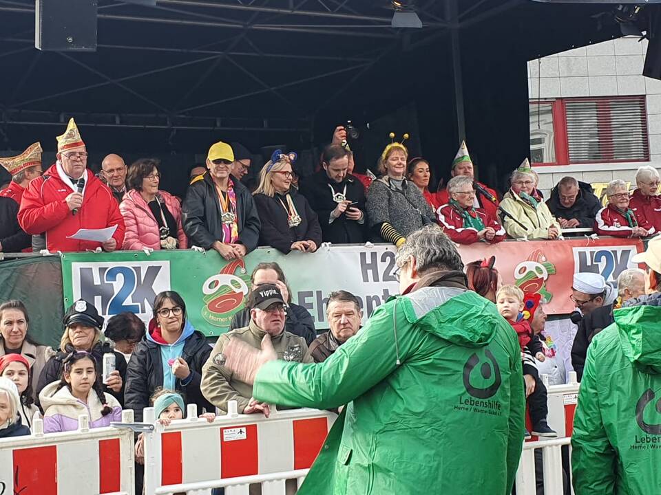 Zwei Personen mit grünen Lebenshilfejacken in einer Menschenmenge.