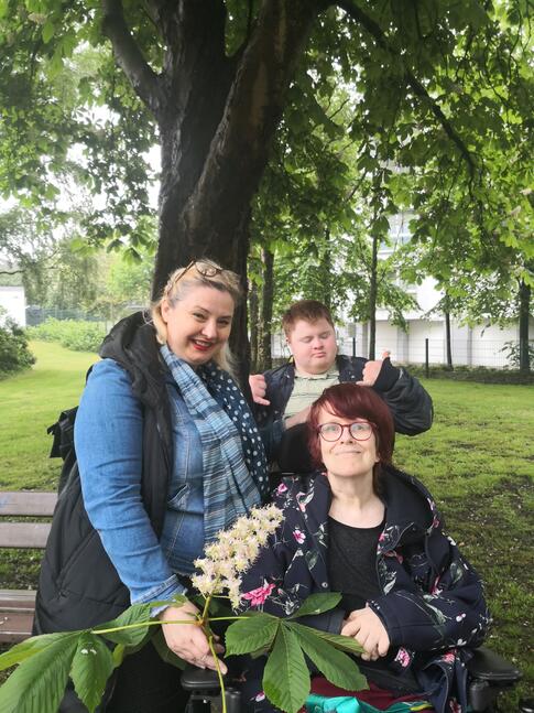 Drei Personen draussen unter einem Baum.