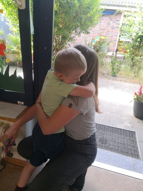 Ein Kind umarmt eine Person die in die Knie gegangen ist.