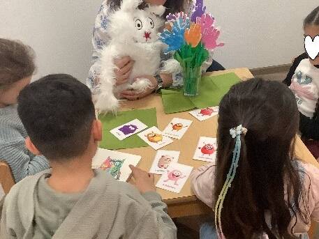 Bild zwei zeigt Kinder am Tisch und eine Frau